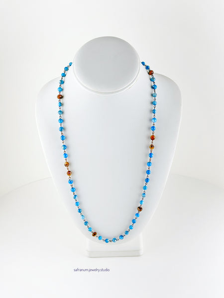 Necklace with blue and brown beads on a mannequin against a white background